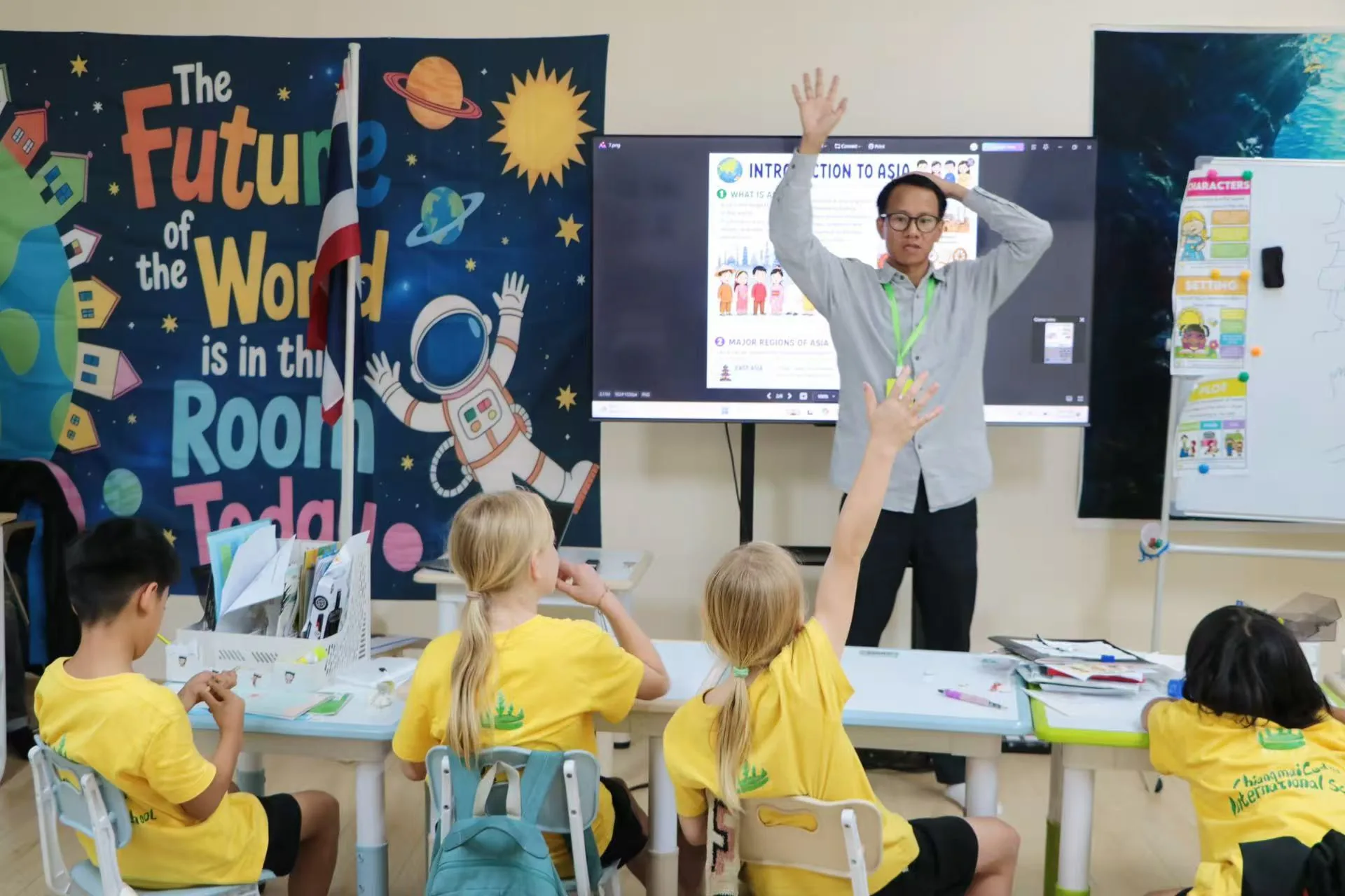 A teacher leading an "Introduction to Asia" lesson as students raise their hands